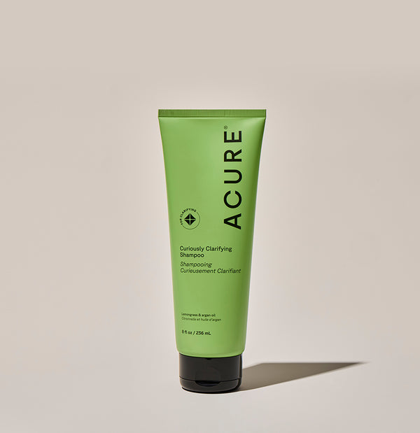 Green shampoo tube with 'ACURE' branding on a beige background