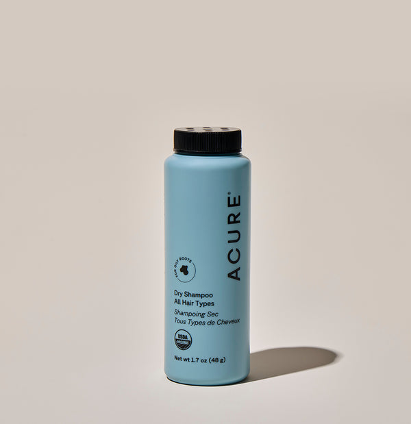 Blue bottle of Acure dry shampoo on a beige background