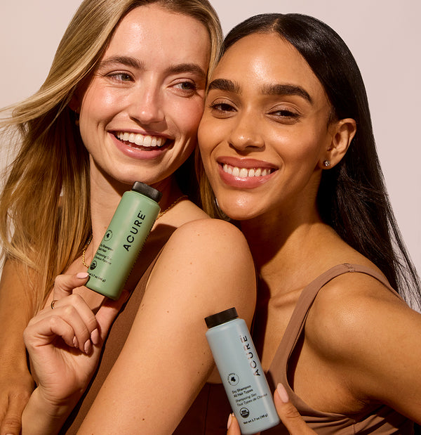 Two women holding Acure skincare products against a neutral background