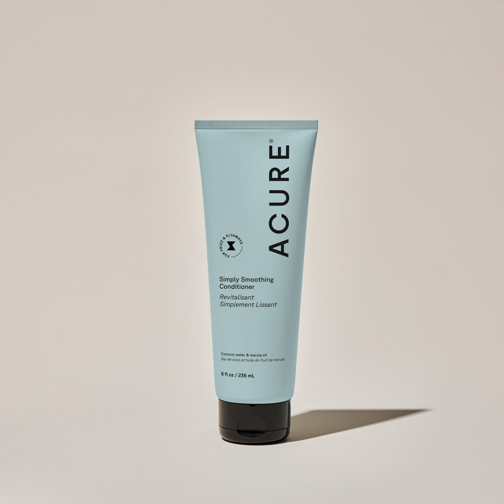 Acure Simply Smoothing Conditioner tube on a beige background