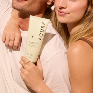 Person holding a tube of Acure product with a neutral background