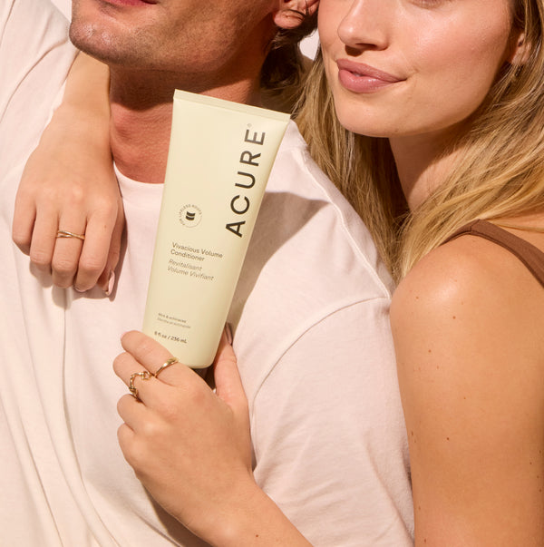 Person holding a tube of Acure product with a neutral background